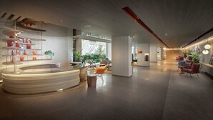 Een moderne hotellobby met een centraal gelegen receptie, een zithoek en grote ramen voor veel daglicht.