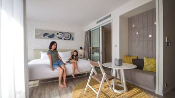 A modern hotel room with a bed, a sofa, a small table, and a chair.