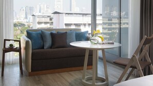 Een moderne hotelkamer met een groot raam, een bank, een kleine tafel met een vaas en een stoel.