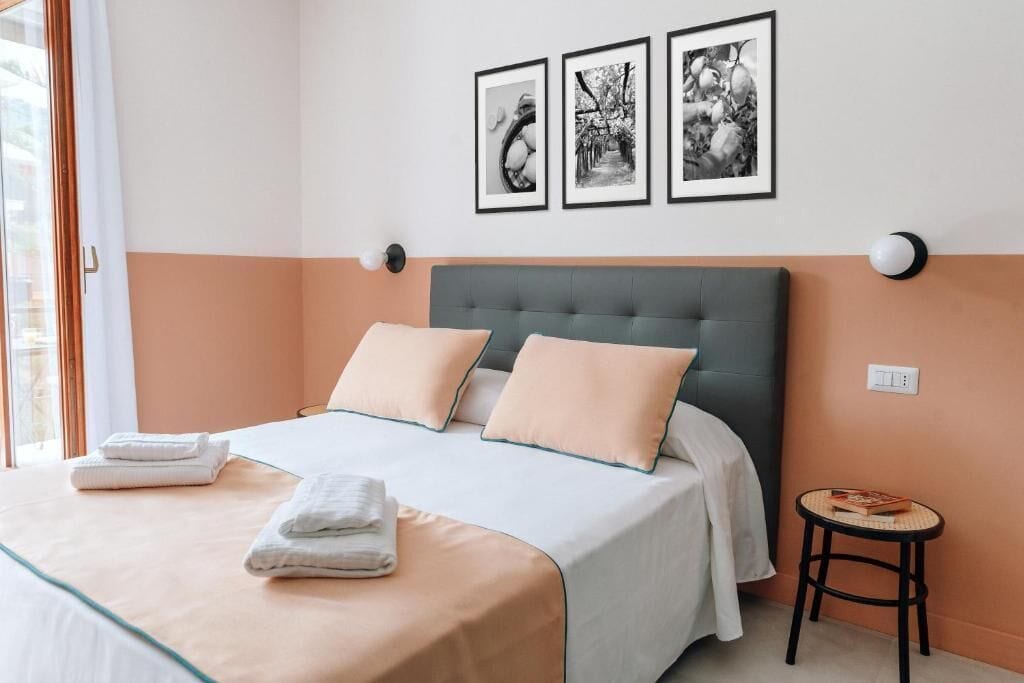 Quarto com cama, almofadas, mesa de cabeceira e decoração na parede.