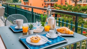 A balcony with breakfast setup including a croissant, muffin, coffee, and orange juice. - Sorrento Colors&Suites (Sorrento)