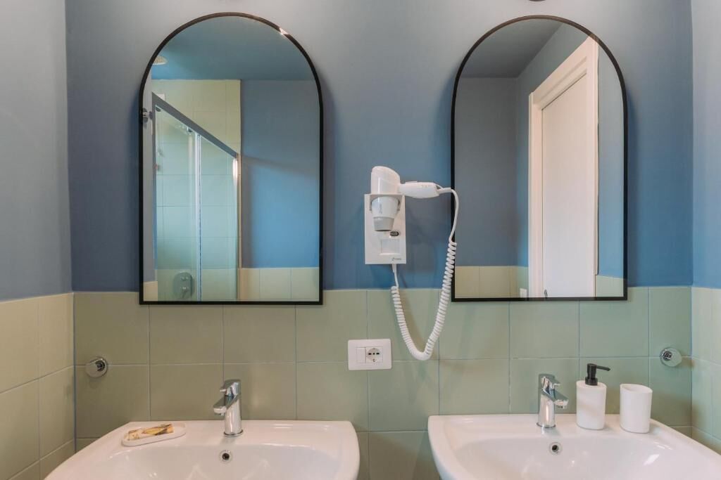 Ein Badezimmer mit zwei Waschbecken, einem Föhn und einem Spiegel.