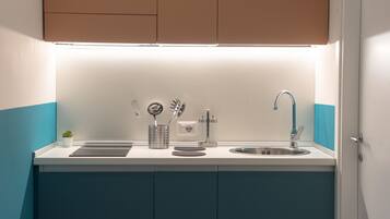 Una cocina moderna con encimera blanca, pileta de acero inoxidable y armarios azules.