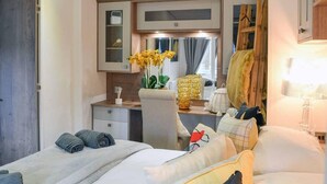 A hotel room with a bed, a desk, a chair, a mirror, and a wardrobe. - Boutique Lodge With hot tub Sleeps 6 (Bridlington)