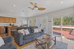 A spacious living room with a grey sofa, a wooden coffee table, and a ceiling fan. - *Pelican Pass* Golf/Fish/Swim / Incredible water views! (Pass Christian)