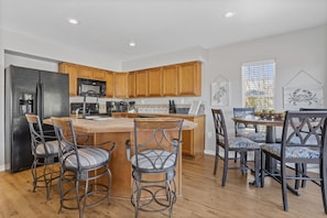 A modern kitchen with wooden cabinets, a stainless steel refrigerator, and a central island with bar stools. - *Pelican Pass* Golf/Fish/Swim / Incredible water views! (Pass Christian)