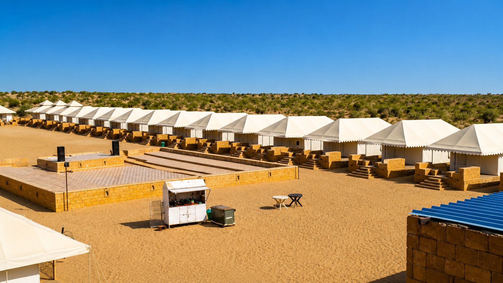 Un complexe hôtelier situé dans le désert, comprenant plusieurs tentes, un stand de restauration et offrant une vue dégagée sur le paysage environnant.