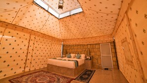 A room with a bed, a nightstand, a stone wall, and a skylight. - The Carvaan Resort (Jaisalmer)