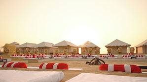 A row of tents with attached lounge chairs and tables, arranged in a row. - The Carvaan Resort (Jaisalmer)