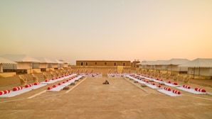 A desert resort with multiple white tents, rows of lounge chairs, and sunbeds arranged in a symmetrical layout. - The Carvaan Resort (Jaisalmer)