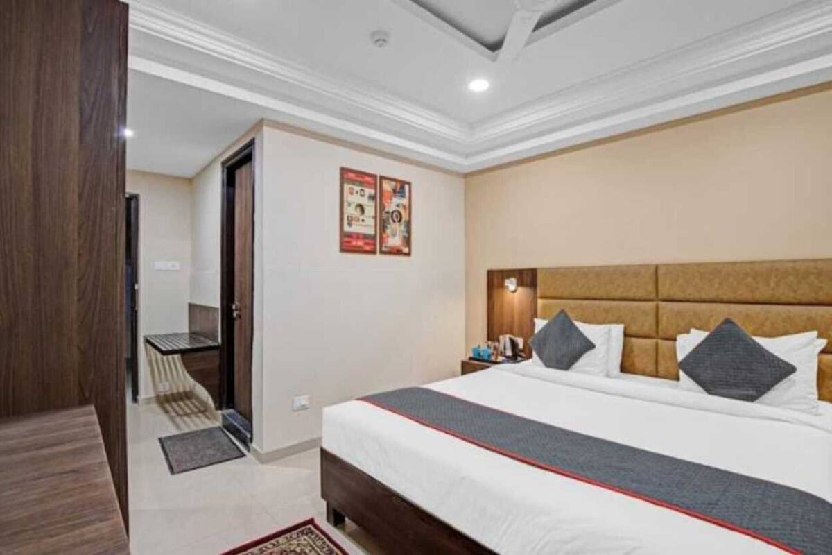 A hotel room with a large bed, a nightstand, a desk, and a door leading to a bathroom.