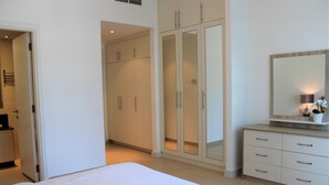 Une chambre à coucher comprenant un lit, une armoire et une coiffeuse avec un miroir.