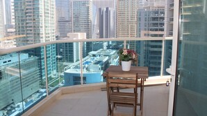 Un balcon avec une table et des chaises en bois, une plante en pot et une vue sur la ville.