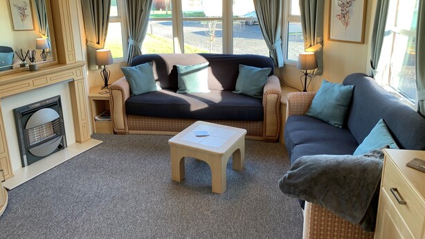 Una sala de estar acogedora con un sofá, dos sillones, una mesa de centro y una chimenea.
