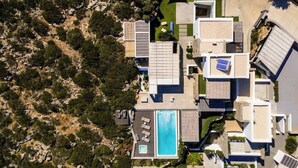An aerial view of a modern residential property with a swimming pool, solar panels, and a well-maintained garden.