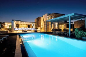 Un espace moderne aménagé au bord de la piscine, avec une piscine à eau claire, des chaises longues et un coin salon abrité.
