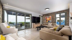 A modern living room with a large sliding glass door leading to a balcony, a flat-screen TV, and a stone accent wall.