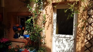 A balcony with potted plants and flowers, a white door, and a window.
