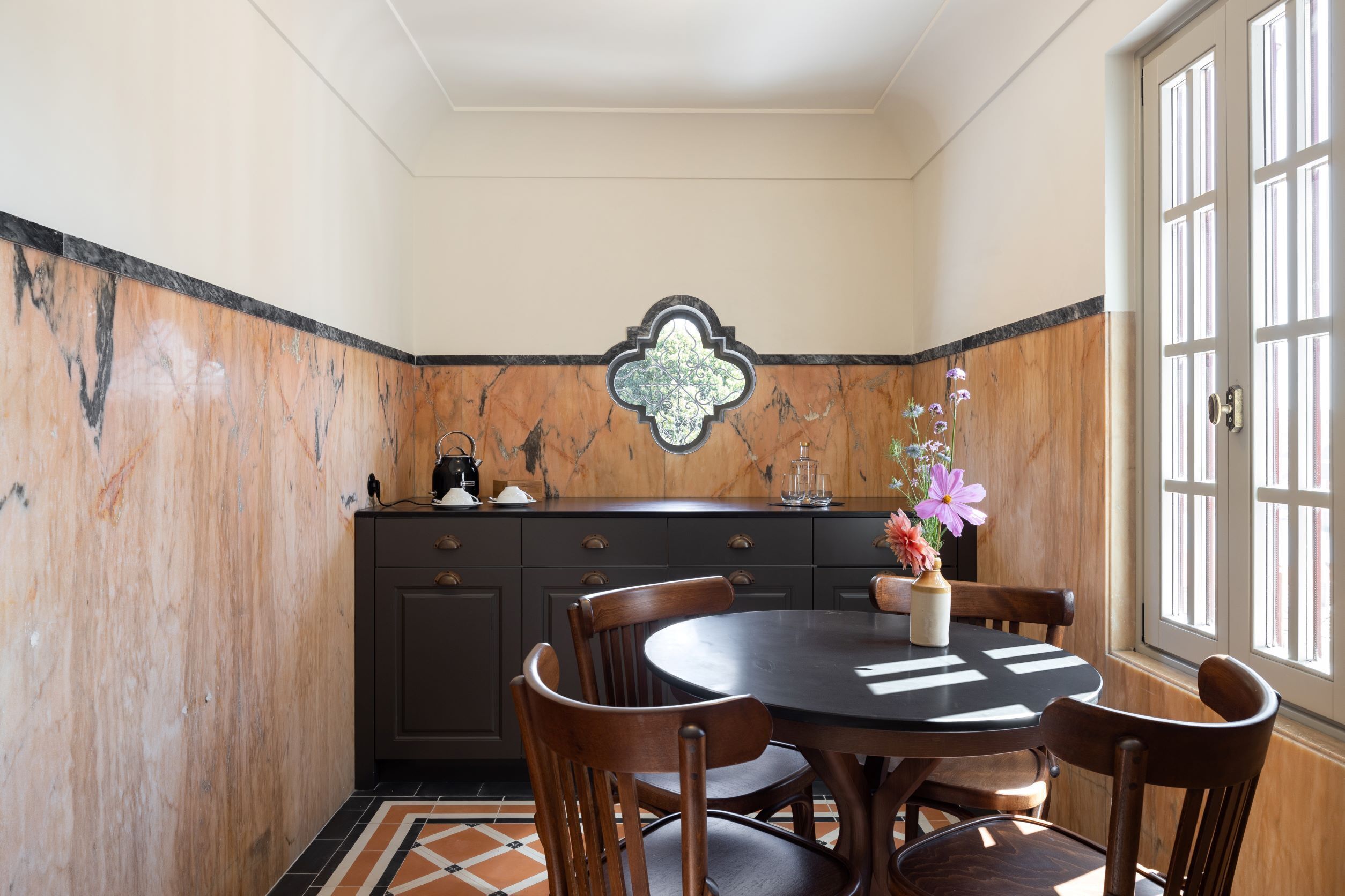 Un comedor con una mesa redonda, sillas de madera, un aparador de madera oscura y un adorno en la pared.
