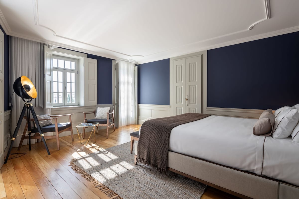 Une chambre avec un grand lit, un bureau avec une lampe et une chaise.
