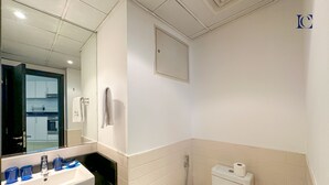 Une salle de bain avec un lavabo blanc, un miroir et des toilettes.