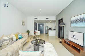 A modern living room with a sofa, coffee table, and TV. There is a kitchen in the background. - KTH - Modern 1BR apartment Dubai Marina (Dubai)