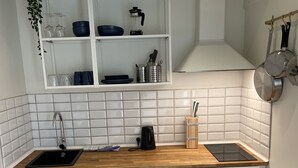 Une cuisine compacte avec des meubles blancs, un plan de travail en bois, un lave-vaisselle encastré et un four.