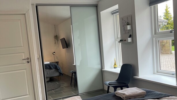 Une chambre d’hôtel avec un lit, une chaise, un bureau, une télévision et une fenêtre.