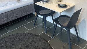 Une petite chambre moderne, avec un lit, une table à manger dressée pour deux personnes et un petit cactus posé sur la table.
