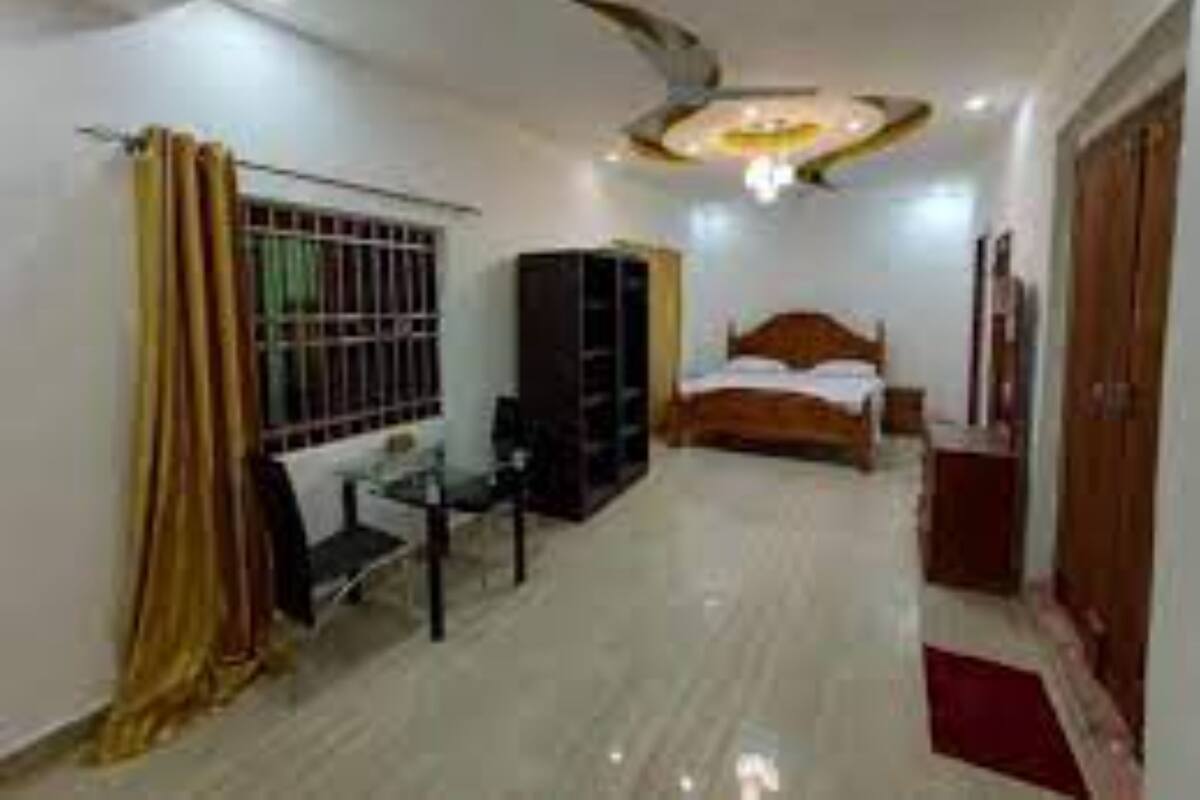 A bedroom with a bed, a desk, a wardrobe, and a ceiling fan.