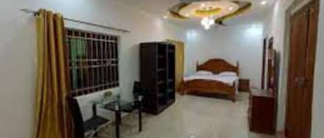 A bedroom with a bed, a desk, a wardrobe, and a ceiling fan.