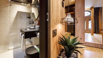 A modern bathroom with a wooden vanity, a mirror, and a hanging light fixture.