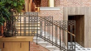 Una escalera con barandilla metálica que conduce a un muro de ladrillo con una ventana.