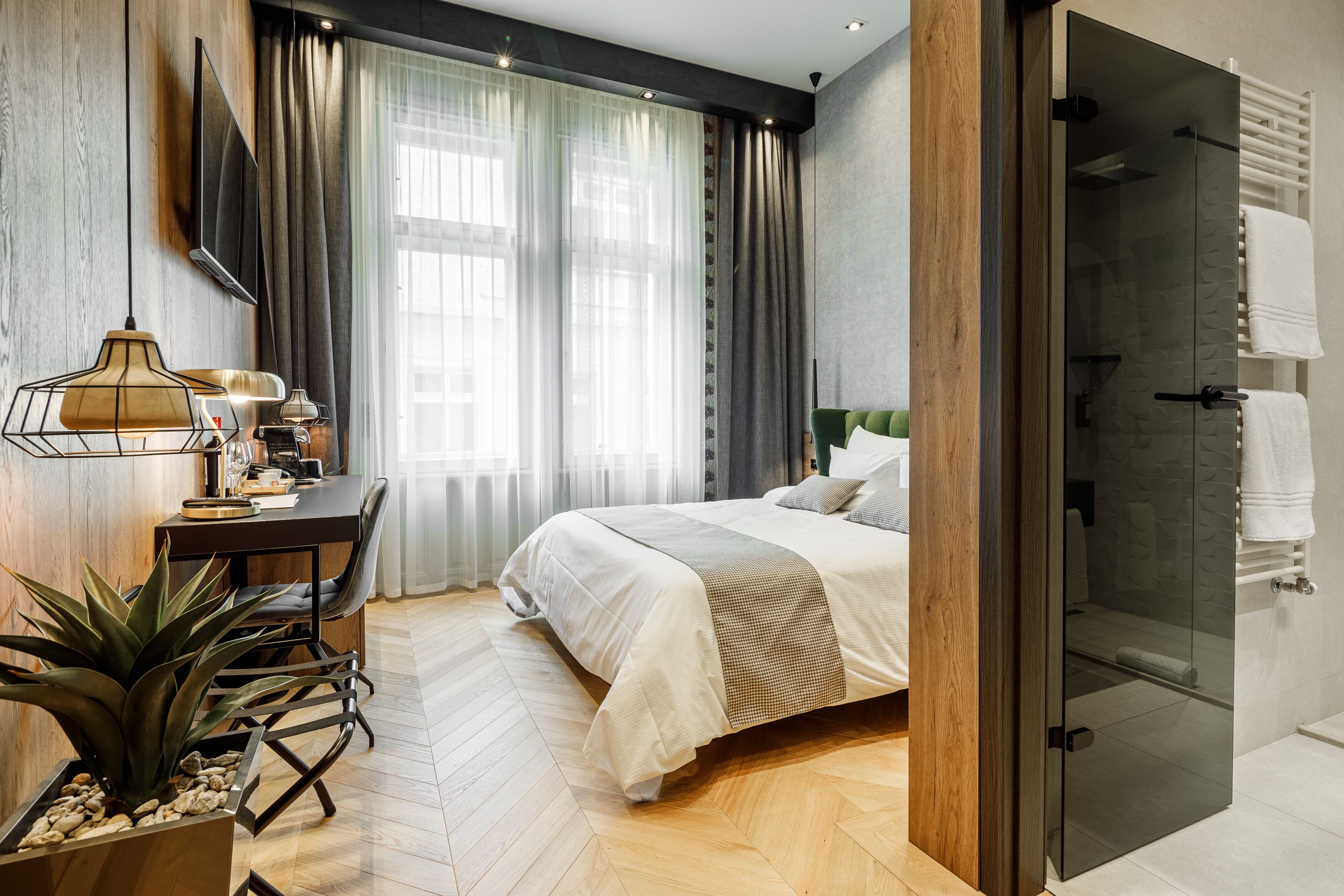 Ein modernes Hotelzimmer mit Bett, Schreibtisch und einer Duschkabine.