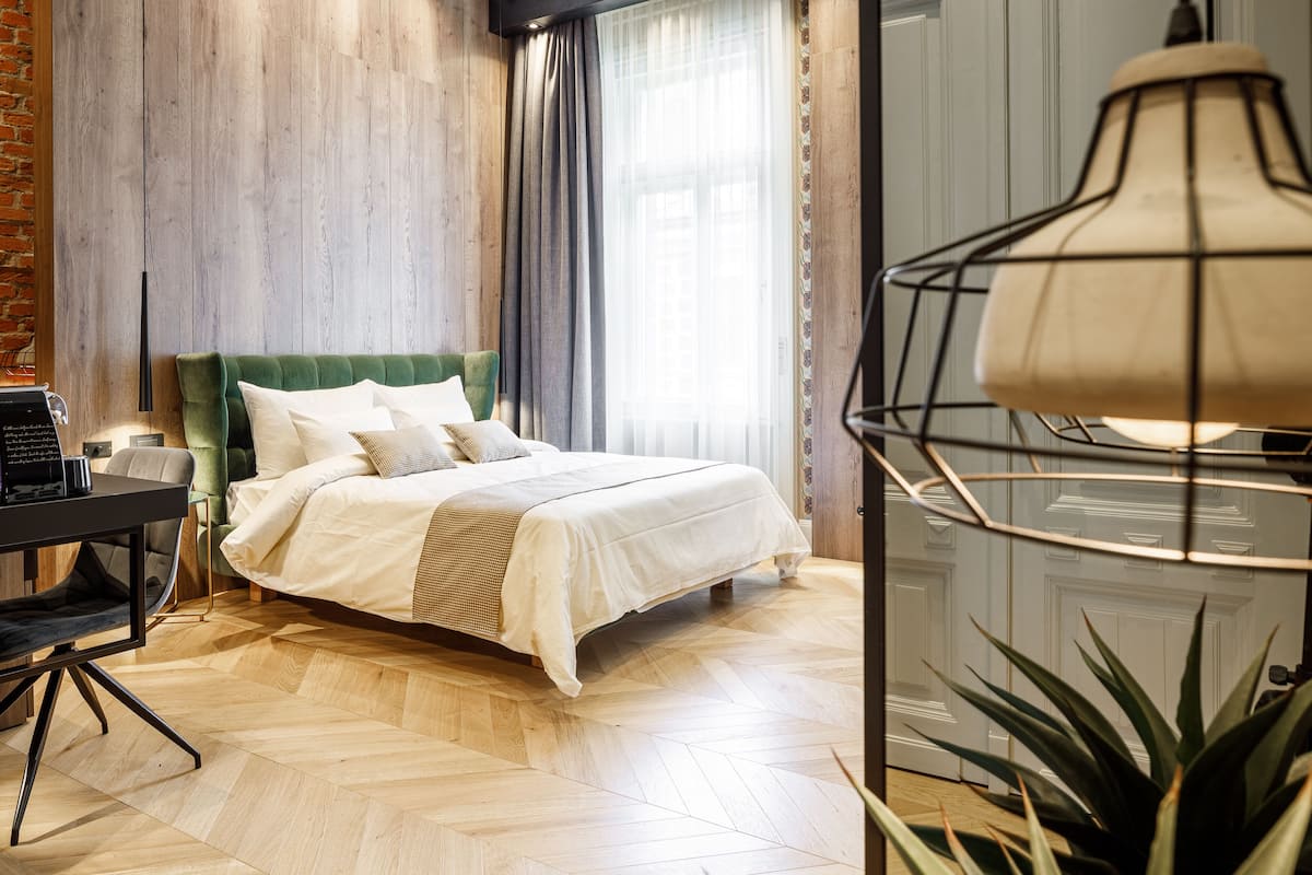 A neatly arranged bedroom with a bed, a desk, and a lamp.