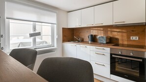 A modern kitchen with white cabinets, a wooden countertop, a built-in oven, and a window with a view of the outside. - Time out in the historic half-timbered house in Bad Buchau  (Bad Buchau)