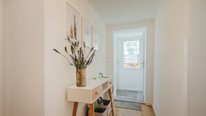 A hallway with a white console table, a vase with dried plants, and a door leading to a bright room. - Time out in the historic half-timbered house in Bad Buchau  (Bad Buchau)