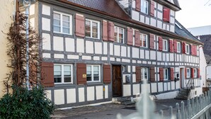 A traditional half-timbered building with a central entrance, a small porch, and a staircase leading to the entrance. - Time out in the historic half-timbered house in Bad Buchau  (Bad Buchau)