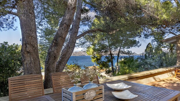Una mesa de madera con sillas y vista al mar.