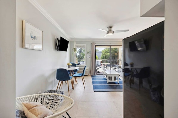 A modern interior with a dining area, a seating area with a chair, and a television mounted on the wall.