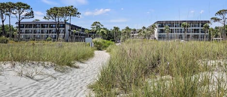 A pathway leading to modern buildings with a clear sky and vegetation.