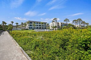 A modern hotel with multiple floors, a paved walkway, and lush greenery.
