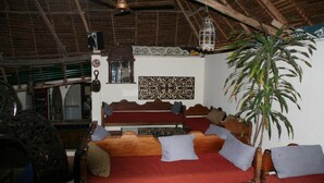 A room with a wooden bed, red bedding, a hanging plant, and a decorative wall piece.