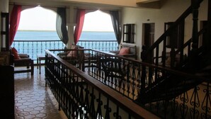 A spacious balcony with a view of the sea, furnished with chairs and a table.
