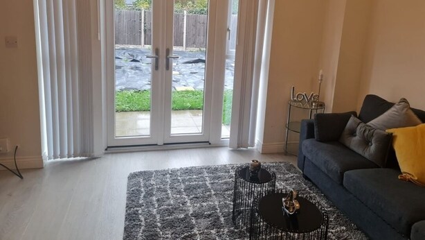 Ein Wohnzimmer mit einem dunkelgrauen Sofa, einem schwarzen Couchtisch und einem grauen Teppich.