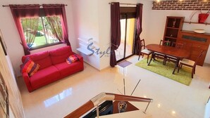 A modern living room with a red sofa, a dining table, and a staircase. - Luxury apartment with spa, 5min. to the sea and golf course (Orihuela Costa)
