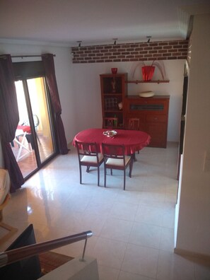A dining area with a round table and chairs, a wooden cabinet, and a red tablecloth. - Luxury apartment with spa, 5min. to the sea and golf course (Orihuela Costa)