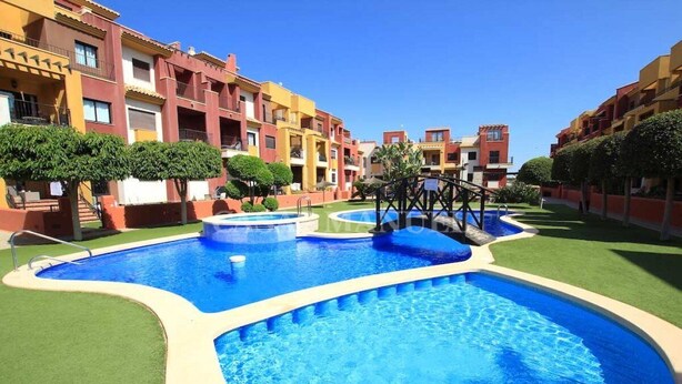 A swimming pool area with multiple pools, surrounded by multi-story buildings with balconies. - Luxury apartment with spa, 5min. to the sea and golf course (Orihuela Costa)