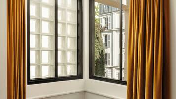 A corner room with a large window, a white bedside table, and a book.