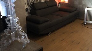 A living room with a sofa, a lamp, and a wall with a tropical leaf pattern. - Large F2 in private residence (Ajaccio)